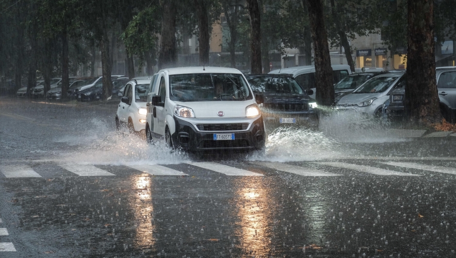 Persone si riparano dalla pioggia con un ombrello durante un temporale a Milano, 5 settembre 2024. ANSA/MATTEO CORNER