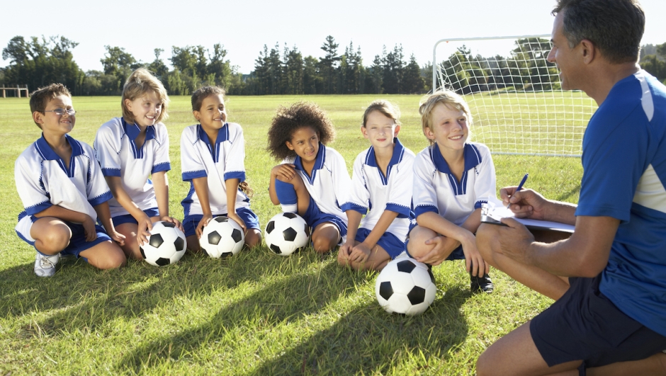 Group Of Children In Soccer Team Having Training With Coach