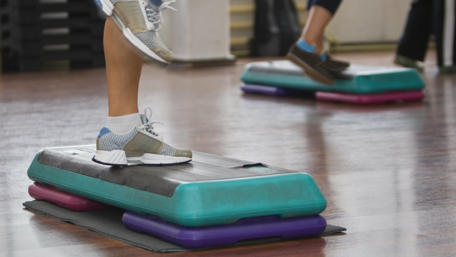 Image of legs doing step aerobics indoors.