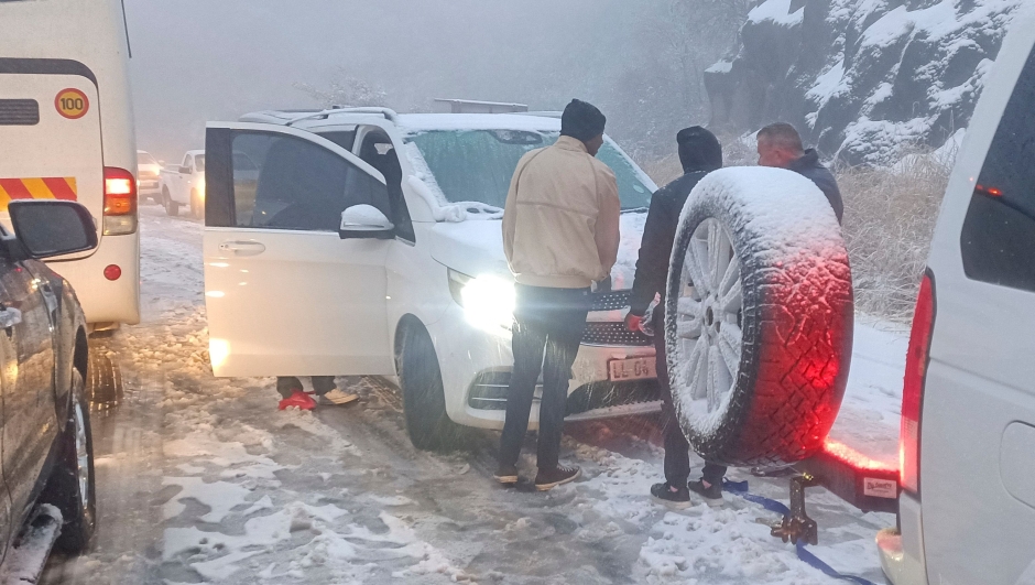 People attempt to free a car stuck in heave snowfall on Oliviershoekpass near Harrismith on September 20, 2024. Unusually heavy snowfall caused major disruption on South Africas roads on September 21 with people still stranded at midday after spending the night stuck in their vehicles. The key N3 highway linking Johannesburg and the east coast city of Durban was one of the worst affected and several portions were closed, with even detours impassible, officials said. (Photo by Grant Bruce Cameron-Ellis / AFP)