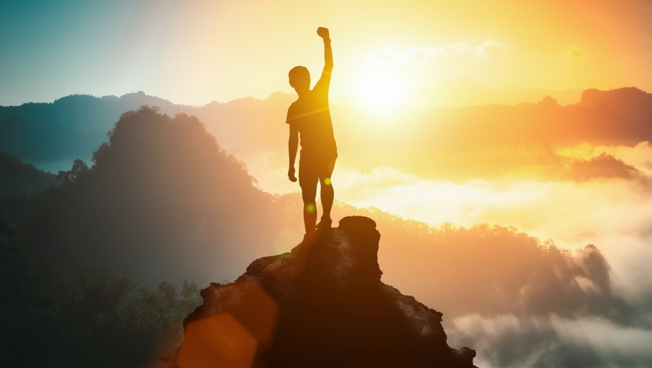 Silhouette of positive man celebrating on mountain top, with arms raised up, silhouette of man standing on the hill, Business, success,victory,leadership,achievement concept. Freedom travel adventure.