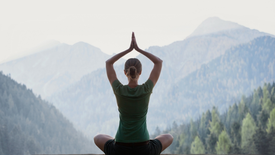 Girl is practicing yoga with mountains at background. Relaxation exercises, meditation, healthy lifestyle, self care, yoga, leisure concept