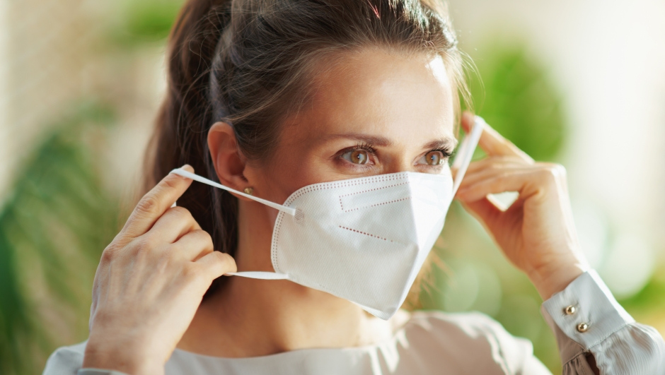 covid-19 pandemic. middle aged woman in grey blouse wearing ffp2 mask.