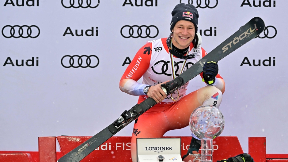 The overall season winner of the Men's FIS Alpine Skiing World Cup Switzerland's Marco Odermatt poses with his trophy on the podium on the last day of the FIS Alpine Skiing World Cup in Saalbach, Austria, after the men's Downhill final event was cancelled due to bad weather conditions, on March 24, 2024. (Photo by Joe Klamar / AFP)