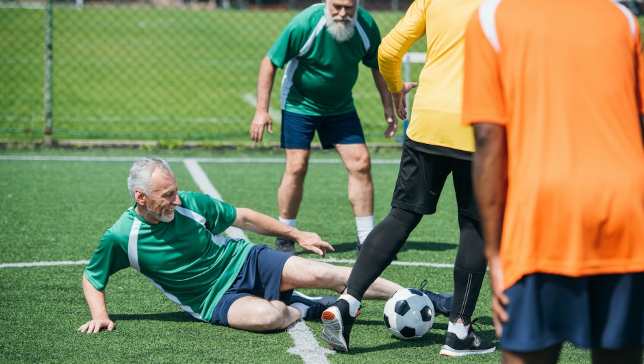 partial view of multicultural elderly friends playing football together