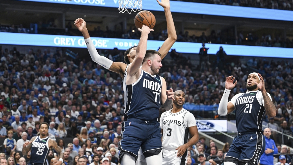 Dallas Mavericks' Luka Doncic , front left, makes a no-look pass behind him through San Antonio Spurs Victor Wembanyama's arms during the second half of an NBA basketball game, Thursday, Oct. 24, 2024, in Dallas, Texas. (AP Photo/Albert Pena)