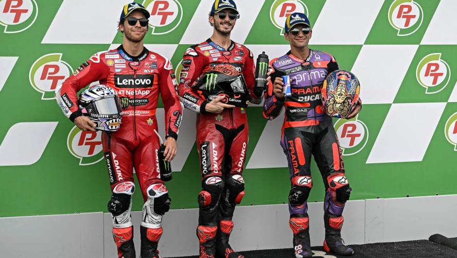 Ducati Lenovo Team's Italian rider Francesco Bagnaia (C) celebrates after coming in pole position next to second position Ducati Lenovo Team's Italian rider Enea Bastianini (L) and third position Prima Pramac Racing's Spanish rider Jorge Martin (R) after the qualifying session of the MotoGP Thailand Grand Prix at the Buriram International Circuit in Buriram on October 26, 2024. (Photo by Lillian SUWANRUMPHA / AFP)