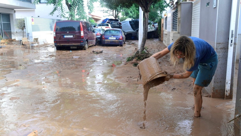 A resident cleans her house next to cars piles due to mudslide in a flooded area in Picuana, near Valencia, eastern Spain, on October 30, 2024. Floods triggered by torrential rains in Spain's eastern Valencia region has left 51 people dead, rescue services said on October 30. (Photo by Jose Jordan / AFP)