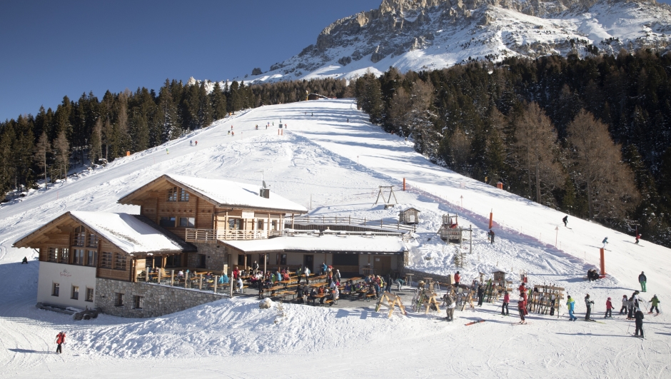 BOLZANO, ITALY - DECEMBER 12: People sitting on the outdoor of a restaurant next to the sky slopes on December 12, 2021 in Obereggen, Italy. Ski facilities remained inactive for two years during the Covid-19 pandemic, re-opening in recent weeks with the hope of boosting tourism, yet with high infection rates and low vaccine turn-out the 2021 season remains uncertain. To combat the rise in Covid-19 cases in Italy, the government tightened health restrictions with a "super green pass" as of December 6.  (Photo by Francesca Volpi/Getty Images)