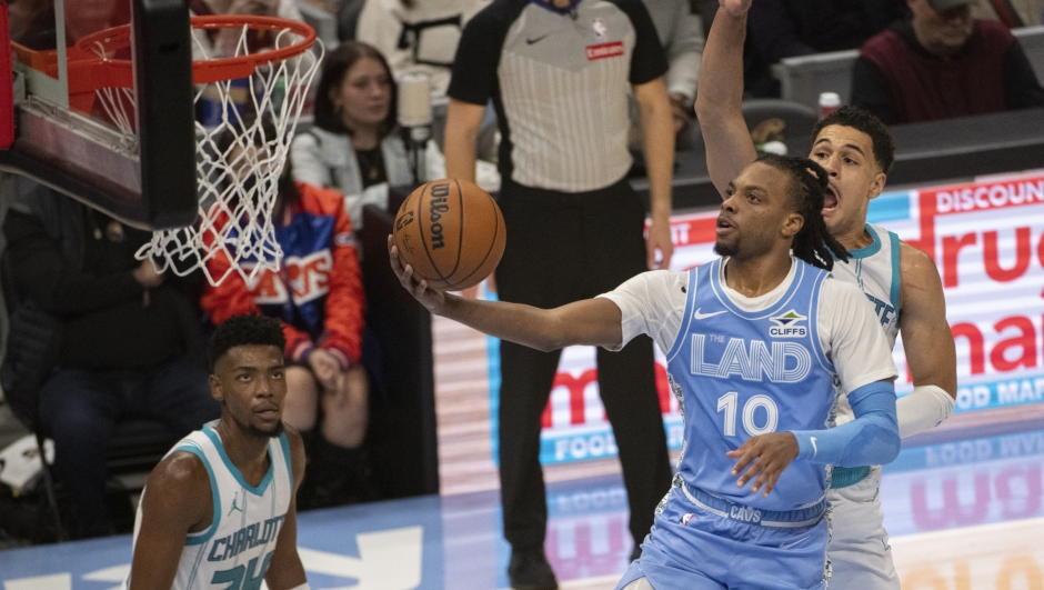 Cleveland Cavaliers' Darius Garland (10) lays in a shot as Charlotte Hornets' Josh Green, right, defends and Hornets' Brandon Miller (24) watches during the first half of an NBA basketball game in Cleveland, Sunday, Nov 17, 2024. (AP Photo/Phil Long)