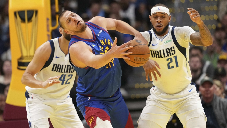 Denver Nuggets center Nikola Jokic, center, bobbles the ball against Dallas Mavericks center Daniel Gafford (21) during the first half of an Emirates NBA Cup basketball game Friday, Nov. 22, 2024, in Denver. (AP Photo/Jack Dempsey)