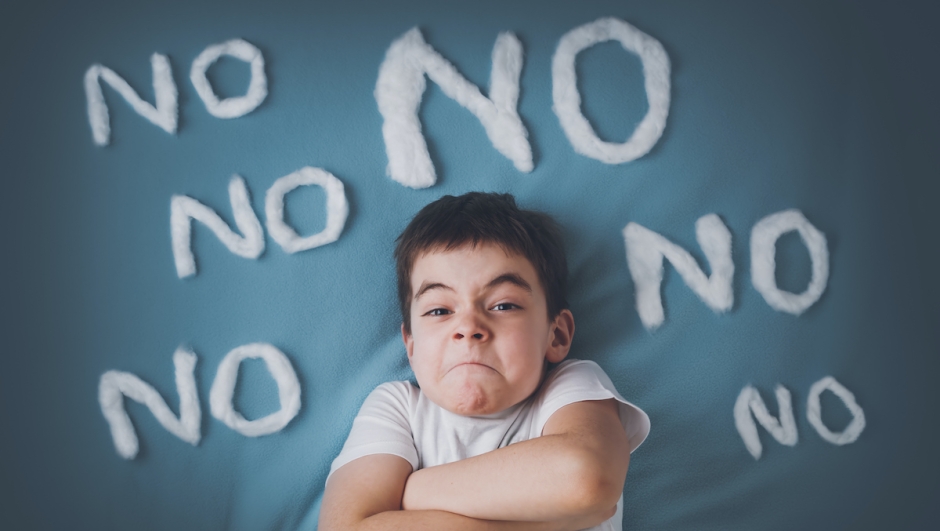 bad boy on blue blanket background. Angry child with no words around