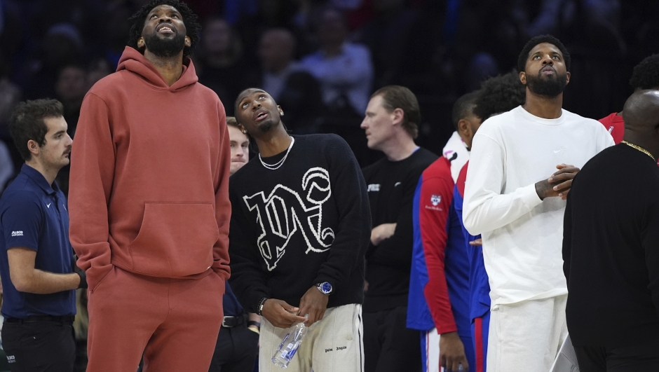 Philadelphia 76ers' Joel Embiid, from left, Tyrese Maxey and Paul George look towards the scoreboard during a timeout during the first half of an NBA basketball game against the Cleveland Cavaliers, Wednesday, Nov. 13, 2024, in Philadelphia. (AP Photo/Matt Slocum)