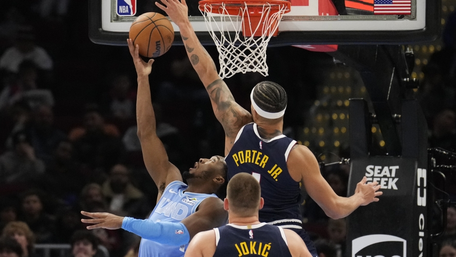 Denver Nuggets forward Michael Porter Jr. (1) defends as Cleveland Cavaliers guard Donovan Mitchell, left, shoots in the second half of an NBA basketball game, Thursday, Dec. 5, 2024, in Cleveland. (AP Photo/Sue Ogrocki)