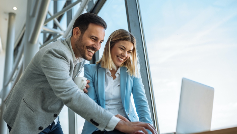 Shot of two happy young businesspeople enjoying working on a laptop.