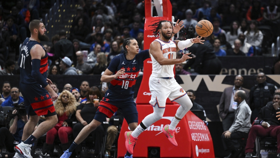 New York Knicks guard Jalen Brunson (11) passes the ball as Washington Wizards forward Kyshawn George (18) defends during the first half of an NBA basketball game, Saturday, Dec. 28, 2024, in Washington. (AP Photo/Terrance Williams)