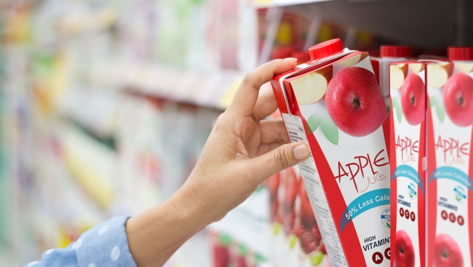 Woman hand choosing to buy apple juice on shelves in supermarket