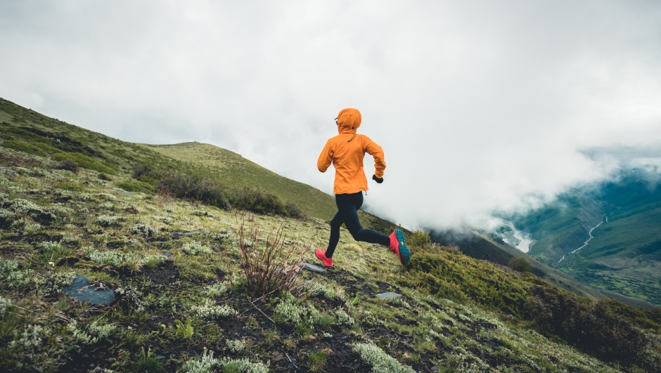 Woman trail runner cross country running at high altitude mountain peak