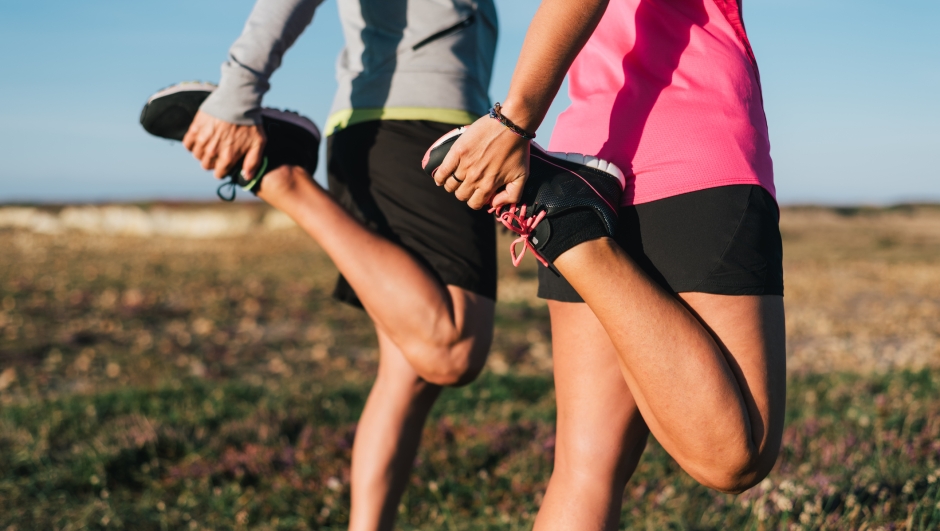 Sporty couple stretching legs outdoors before trail running workout outdoors. Fitness healthy lifestyle concept.