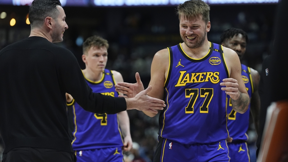 Los Angeles Lakers head coach JJ Redick, left, congratulates guard Luka Doncic as he heads to the bench late in the second half of an NBA basketball game against the Denver Nuggets, Saturday, Feb. 22, 2025, in Denver. (AP Photo/David Zalubowski)