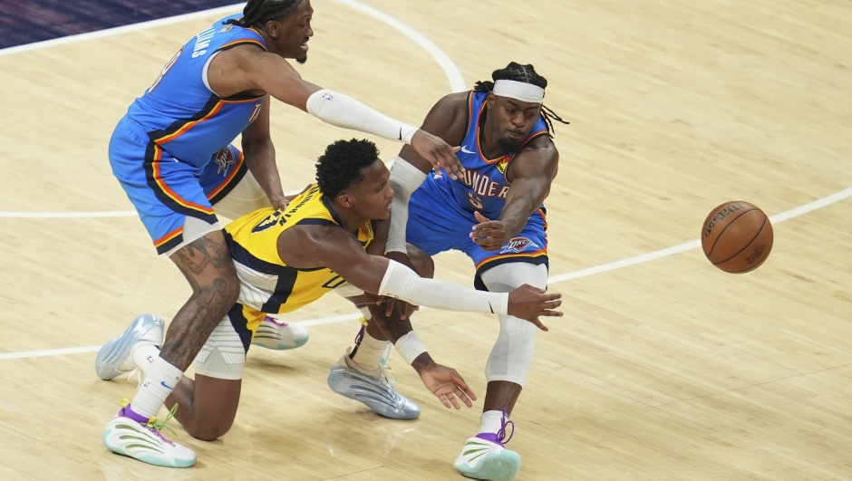 Indiana Pacers guard Bennedict Mathurin passes the ball under pressure from Oklahoma City Thunder forward Jalen Williams, right, during the second half of Game 3 of the NBA Finals basketball series, Wednesday, June 11, 2025, in Indianapolis. (AP Photo/Michael Conroy)