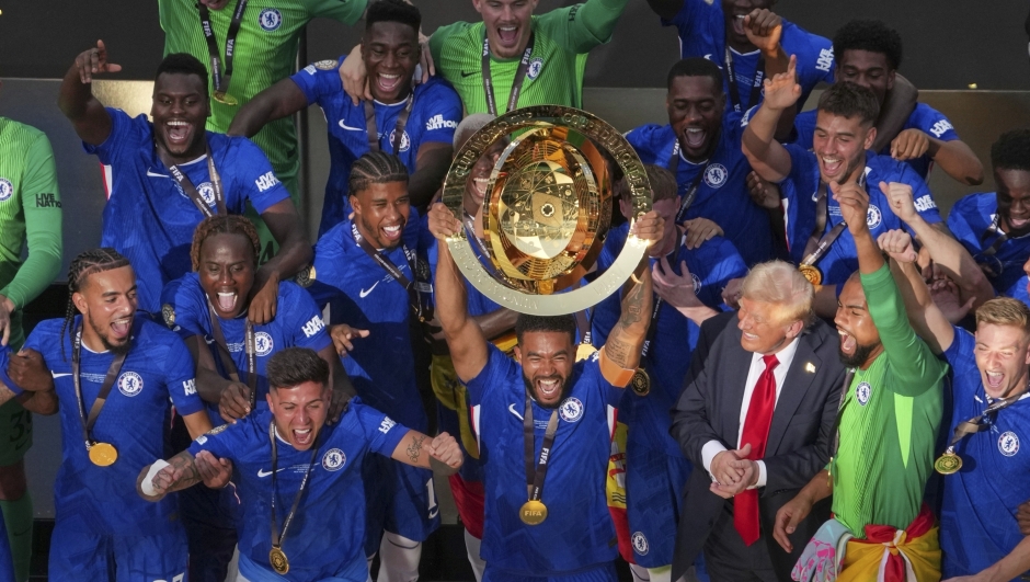 Chelsea team members, accompanied by President Donald Trump, celebrate with the championship trophy after the Club World Cup final soccer match between Chelsea and PSG in East Rutherford, N.J., Sunday, July 13, 2025. (AP Photo/Matt Slocum)