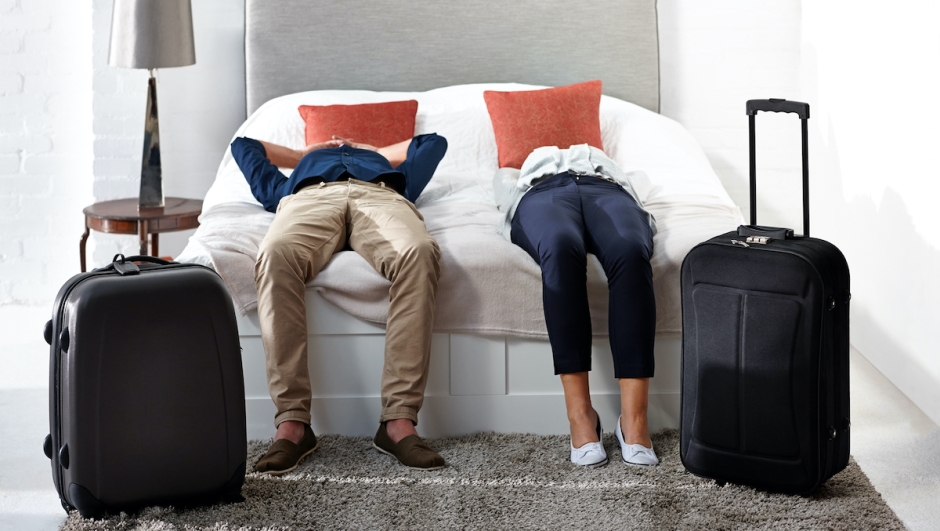Indoor shot of mature couple lying on bed with luggage