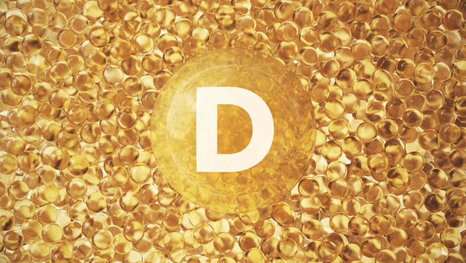 A modern 3D rendering featuring a large yellow transparent capsule marked with the letter "D", surrounded by small glossy gel-like spheres