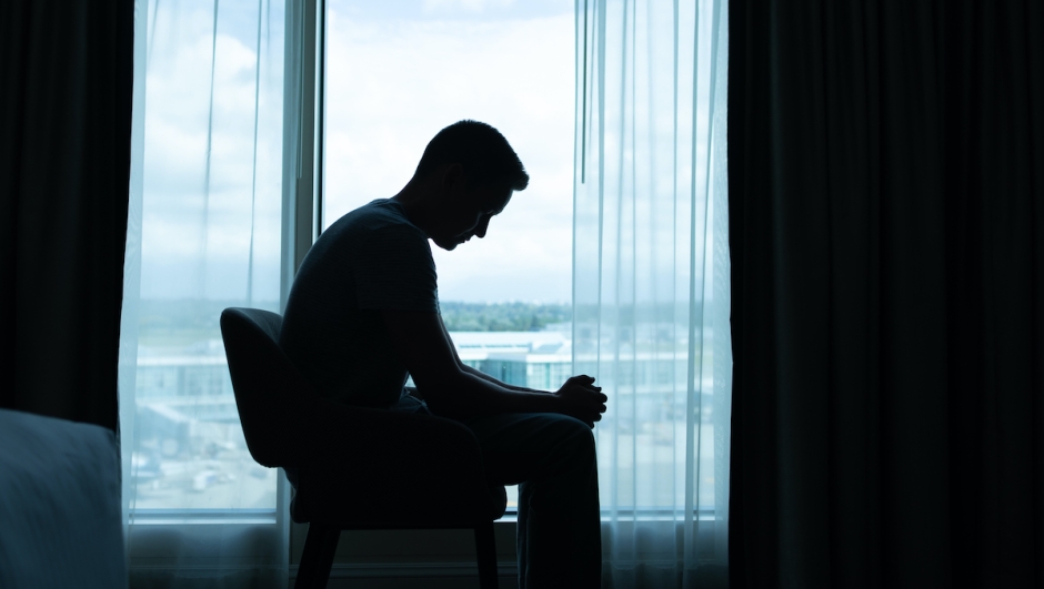Lonely and sad man sitting in the dark room by  himself.