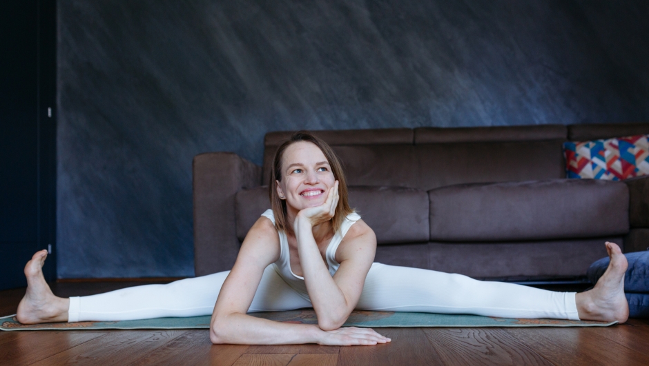 low angle view of a light haired woman doing yoga at home, doing the splits