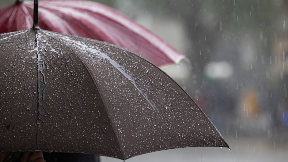 Particular view of a wet grey and red umbrellas after the rain