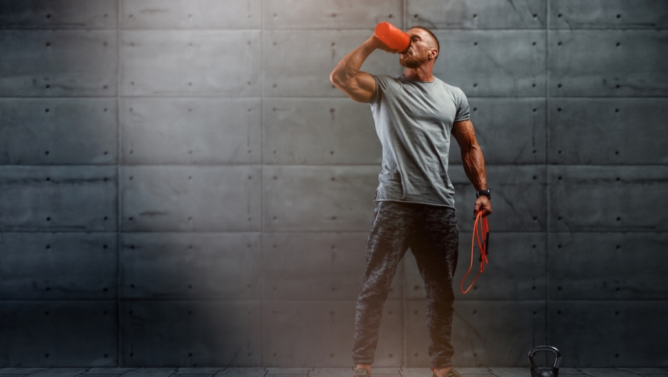 Nutritional Supplement. Muscular Men Drinks Protein, Energy Drink After Workout. Copy Space