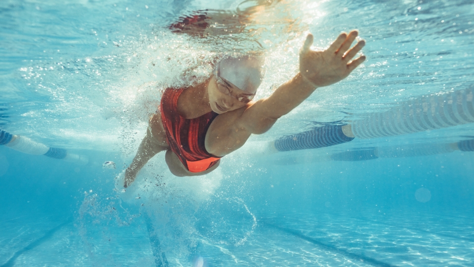 Underwater shot of female athlete swimming in pool. Young woman swimming the front crawl in a pool.