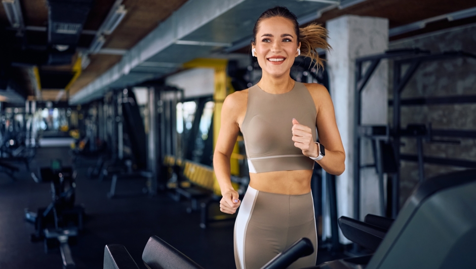 Happy athletic woman jogging on running track in a gym and looking away. Copy space.