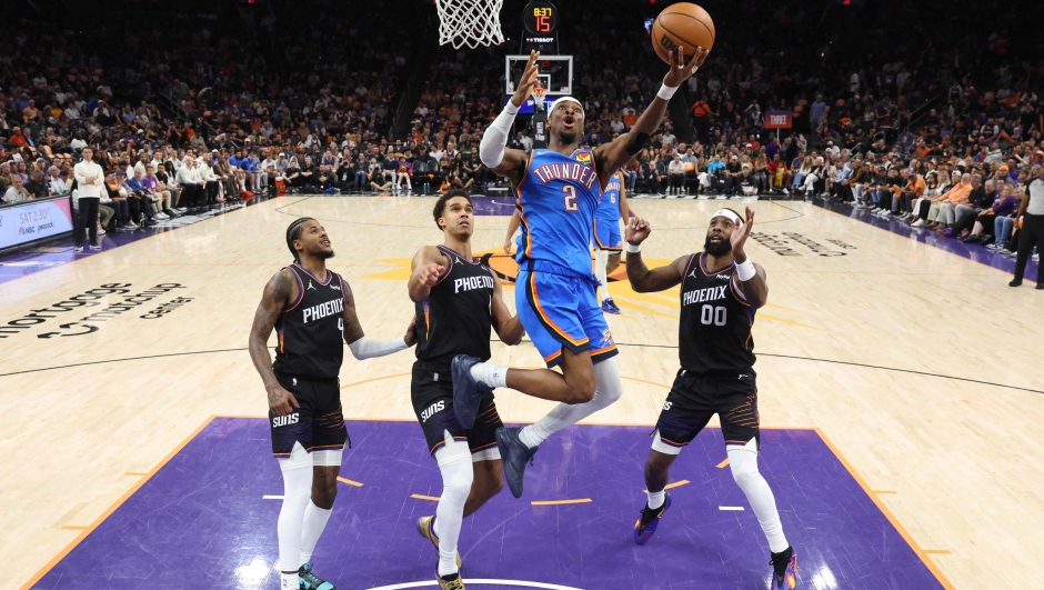  Shai Gilgeous-Alexander #2 of the Oklahoma City Thunder shoots the ball past Jalen Green #4, Devin Booker #1, and Royce O'Neale #00 of the Phoenix Suns during the second quarter in Game Four of the First Round of the NBA Western Conference Playoffs at Mortgage Matchup Center on April 27, 2026 in Phoenix, Arizona. NOTE TO USER: User expressly acknowledges and agrees that, by downloading and or using this photograph, User is consenting to the terms and conditions of the Getty Images License Agreement.   Christian Petersen/Getty Images/AFP (Photo by Christian Petersen / GETTY IMAGES NORTH AMERICA / Getty Images via AFP)