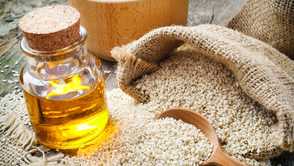 sesame seeds in sack and bottle of oil on wooden rustic table