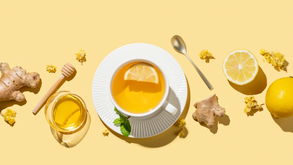 Flat lay of tea with lemon, ginger, honey, and mint in a cup on a yellow background with shadows. Concept of a drink to support immunity and health during the cold season. Advertising or banner menu cafe. Top view, copy space.