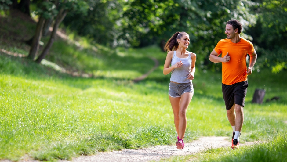 Portrait of happy young fit people running together ourdoors. Couple sport healthy lifetsyle concept