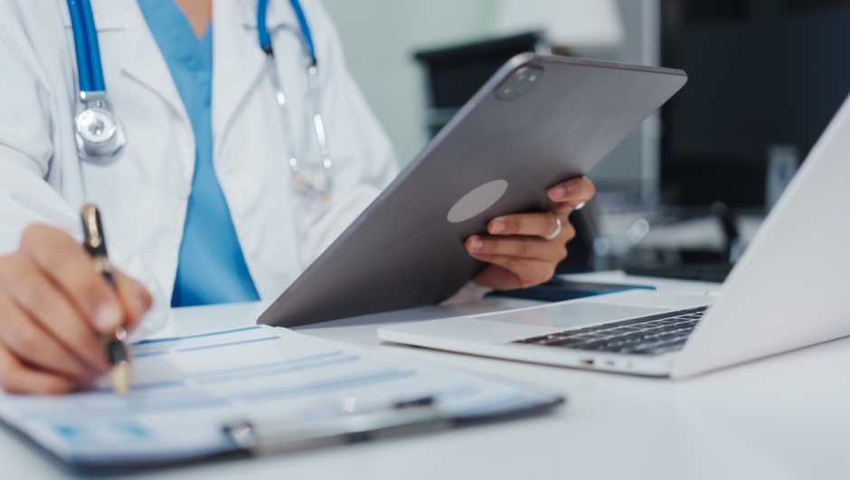 Asian female doctor is reviewing medical records, working on a computer, planning treatment, giving online consultations, and explaining medications to patients via a medical video call in a clinic