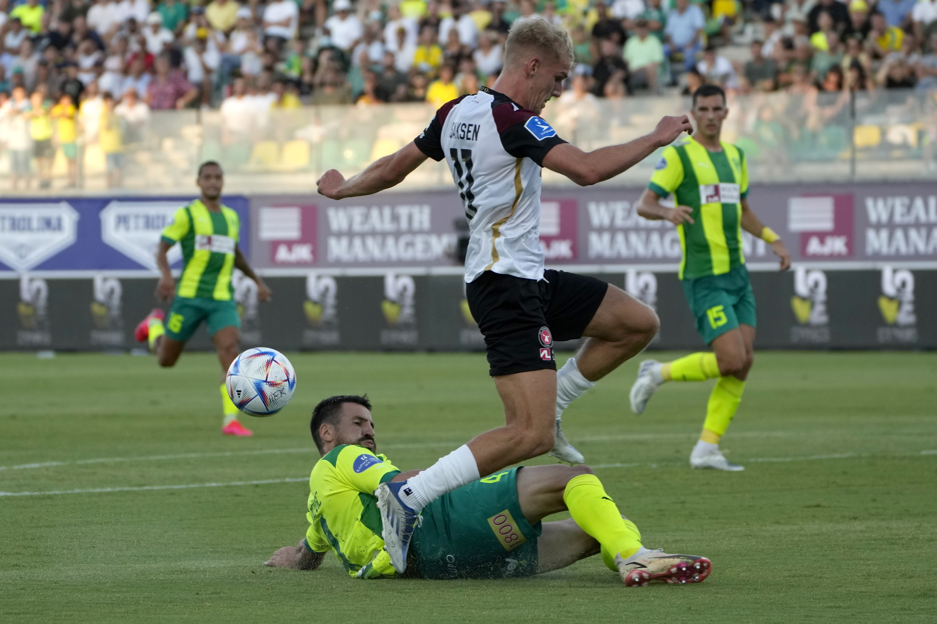 Midtjylland's Gustav Isaksen, top, and AEK's Angel Nenad Tomovic fight for the ball during the Champions League, second qualifying round, second leg match between AEK Larnaca and Midtjylland at AEK arena stadium in southern coastal city of Larnaca, Cyprus, Tuesday, July 26, 2022. (AP Photo/Petros Karadjias)