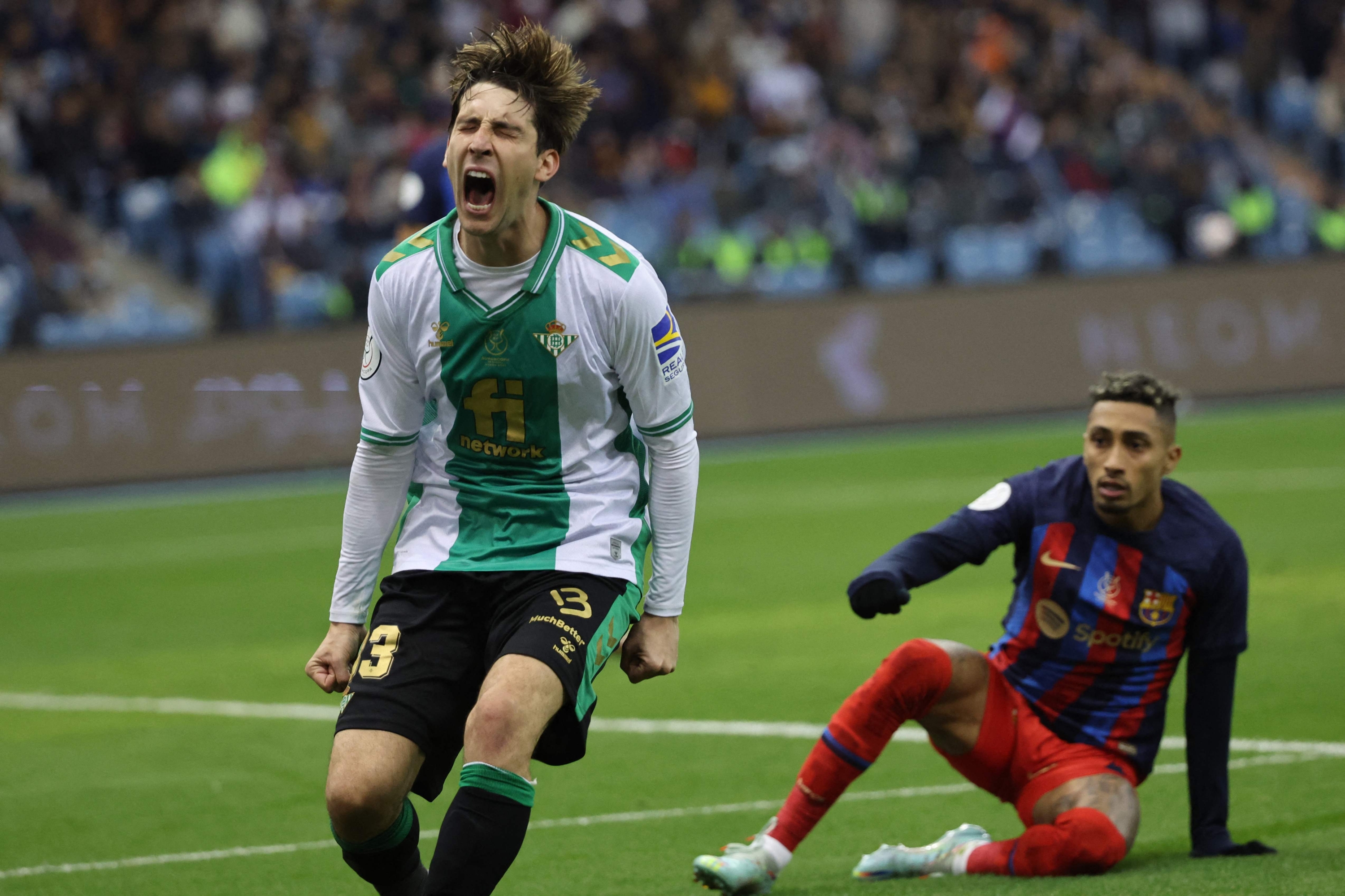 Real Betis' Spanish defender Juan Miranda (L) reacts to a missed chance as Barcelona's Brazilian forward Raphinha sits on the pitch during the Spanish Super Cup semi-final football match between Real Betis and FC Barcelona at the King Fahd International Stadium in Riyadh, Saudi Arabia, on January 12, 2023. (Photo by Giuseppe CACACE / AFP)
