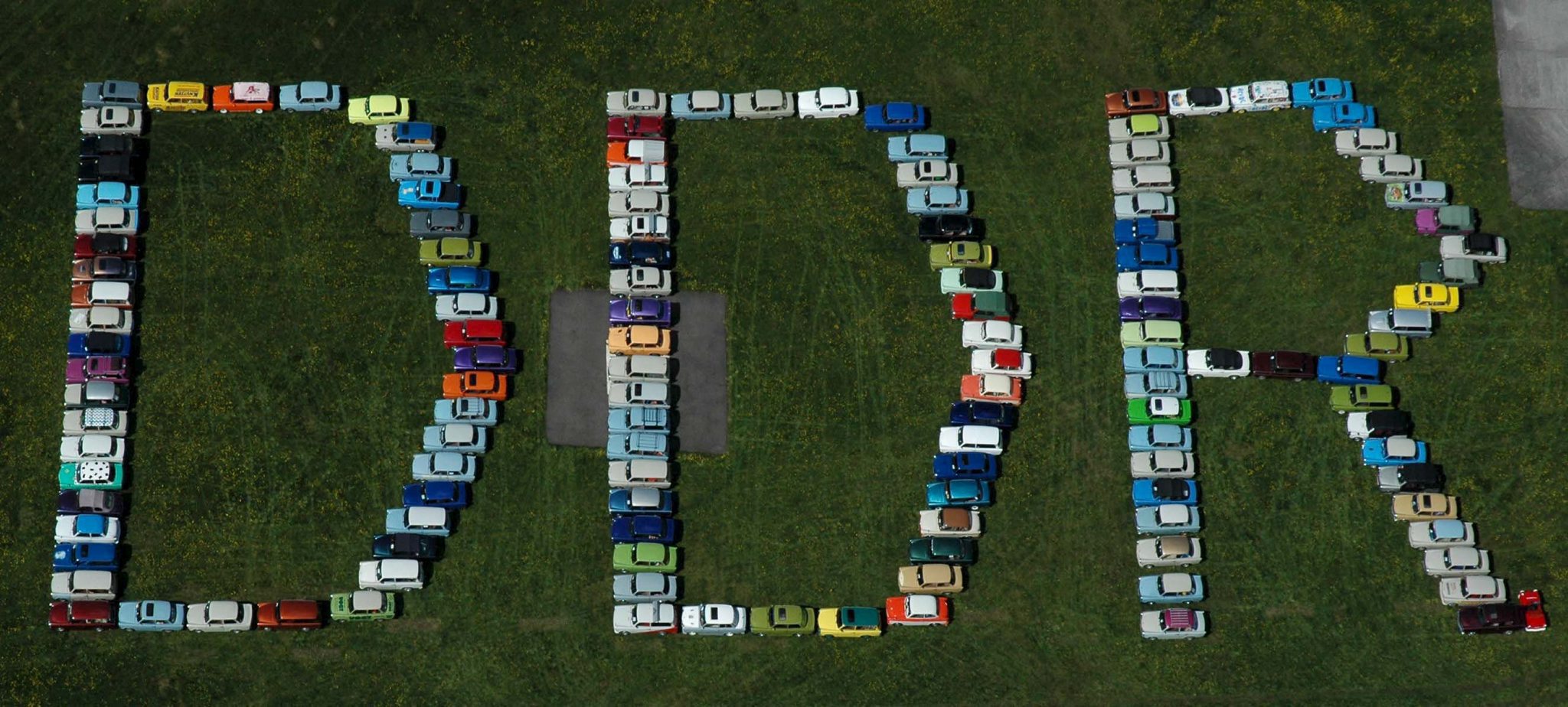 epa000428294 Aerial view dated 07 May 2005 of 135 Trabant cars lined up to build the word DDR (GDR) at the 11th International Trabi meeting at the airport of Anklam, Germany. More than 580 of the legendary cars with the plastic body and thousands of visitors have come to the first of 50 nationwide meetings of Trabi lovers this year.  EPA/STEFAN SAUER