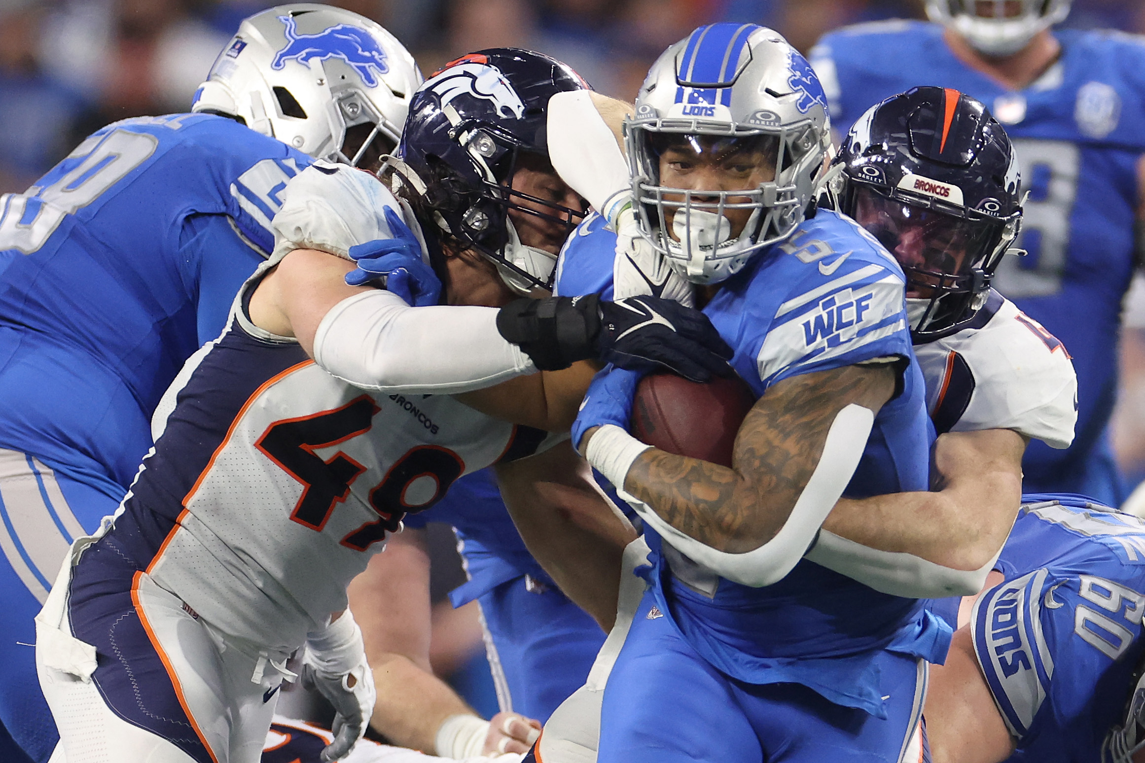 DETROIT, MICHIGAN - DECEMBER 16: David Montgomery #5 of the Detroit Lions runs the ball against Alex Singleton #49 of the Denver Broncos during the fourth quarter at Ford Field on December 16, 2023 in Detroit, Michigan.   Gregory Shamus/Getty Images/AFP (Photo by Gregory Shamus / GETTY IMAGES NORTH AMERICA / Getty Images via AFP)