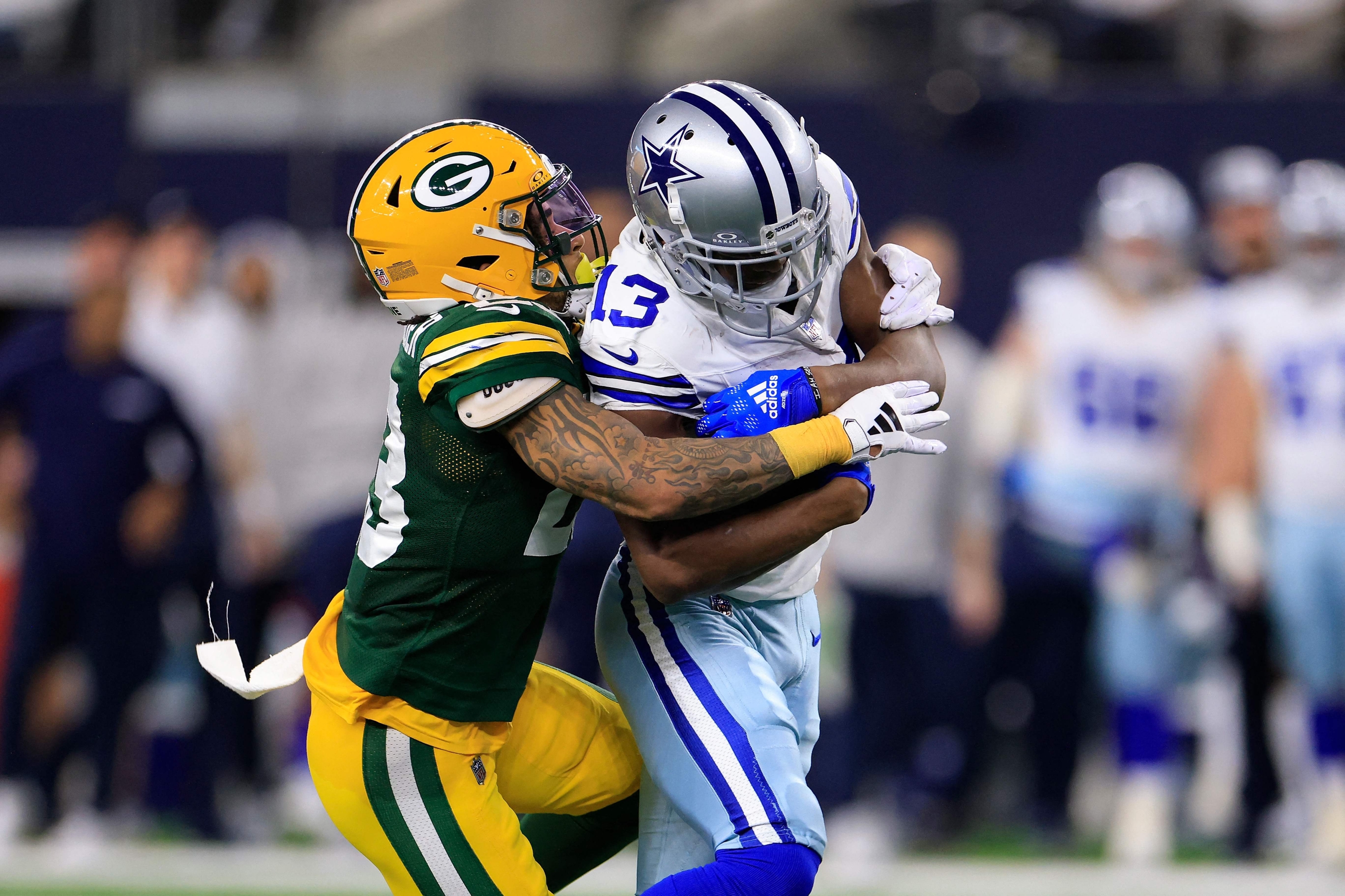 ARLINGTON, TEXAS - JANUARY 14: Michael Gallup #13 of the Dallas Cowboys is brought down by Jaire Alexander #23 of the Green Bay Packers during the third quarter of the NFC Wild Card Playoff game at AT&T Stadium on January 14, 2024 in Arlington, Texas.   Ron Jenkins/Getty Images/AFP (Photo by Ron Jenkins / GETTY IMAGES NORTH AMERICA / Getty Images via AFP)