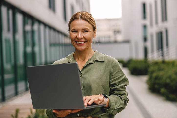Smiling woman manager working laptop on modern building background