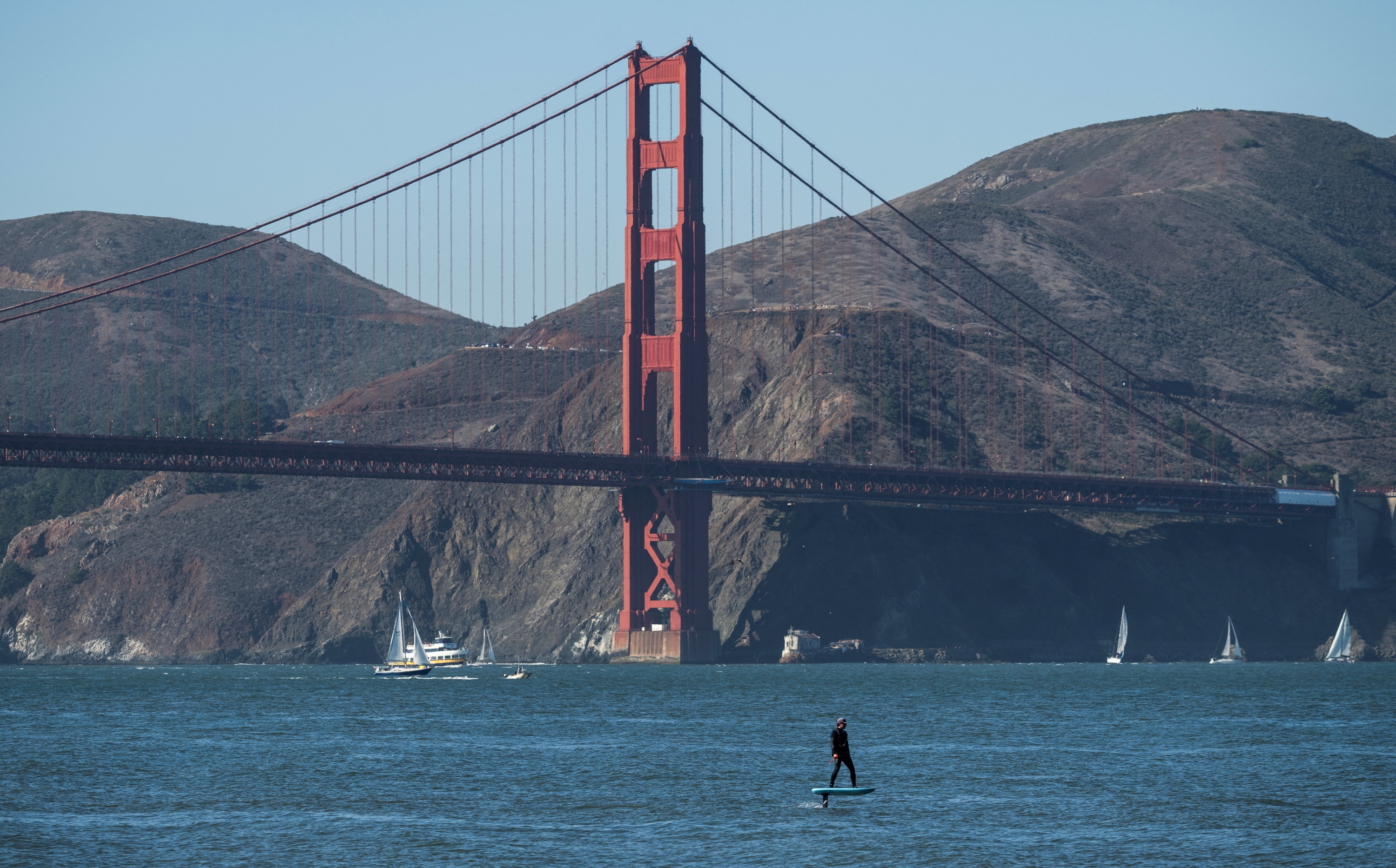 A man foil boards near the Golden Gate Bridge in San Francisco, California, on November 11, 2023. (Photo by ANDREW CABALLERO-REYNOLDS / AFP)