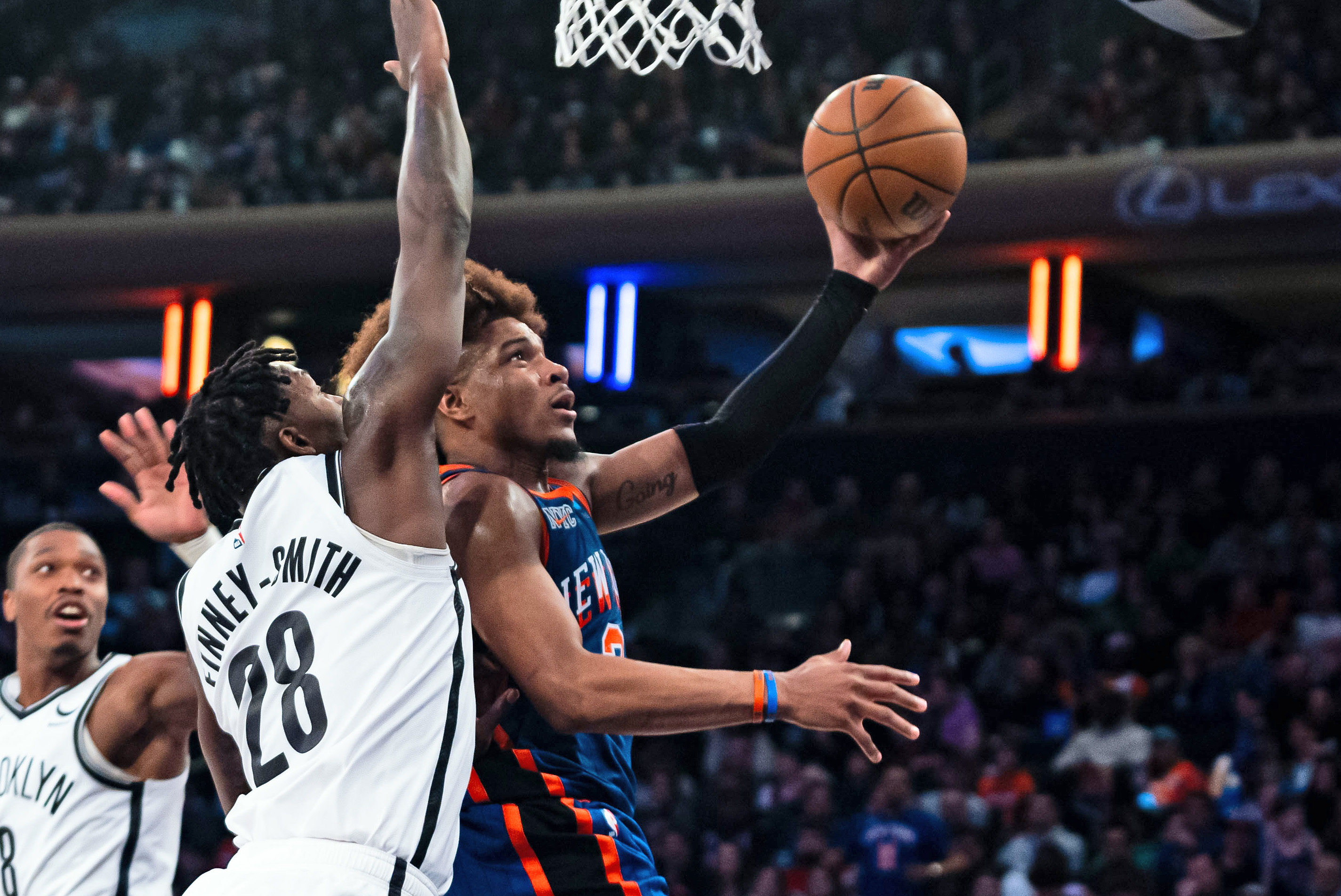 New York Knicks' Miles McBride (2) shoots ahead of Brooklyn Nets forward Dorian Finney-Smith (28) during the second half of an NBA basketball game in New York, Saturday, March 23, 2024. (AP Photo/Peter K. Afriyie)