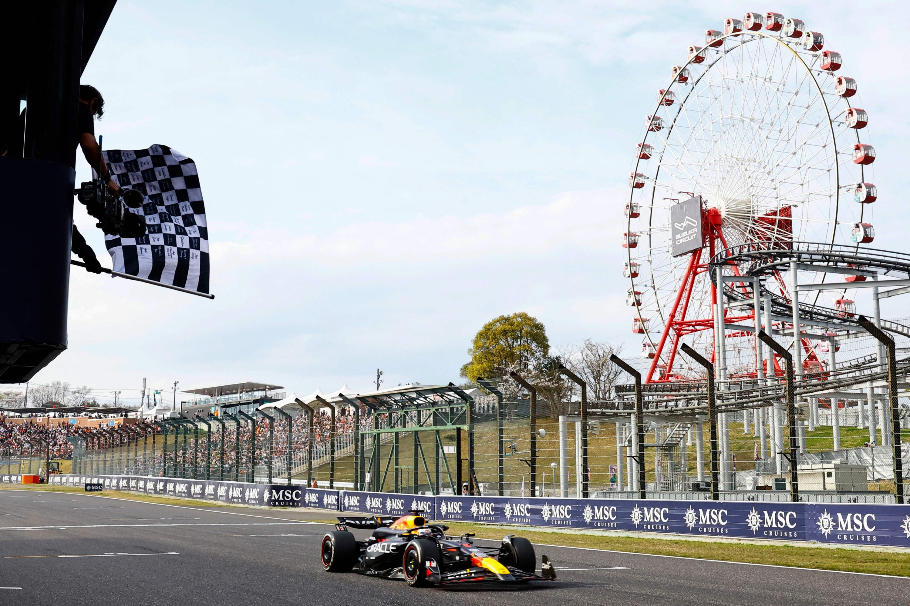 TOPSHOT - A race official waves the chequered flag as Red Bull Racing's Dutch driver Max Verstappen wins the Formula One Japanese Grand Prix race at the Suzuka circuit in Suzuka, Mie prefecture on April 7, 2024. (Photo by KIM Kyung-Hoon / POOL / AFP)