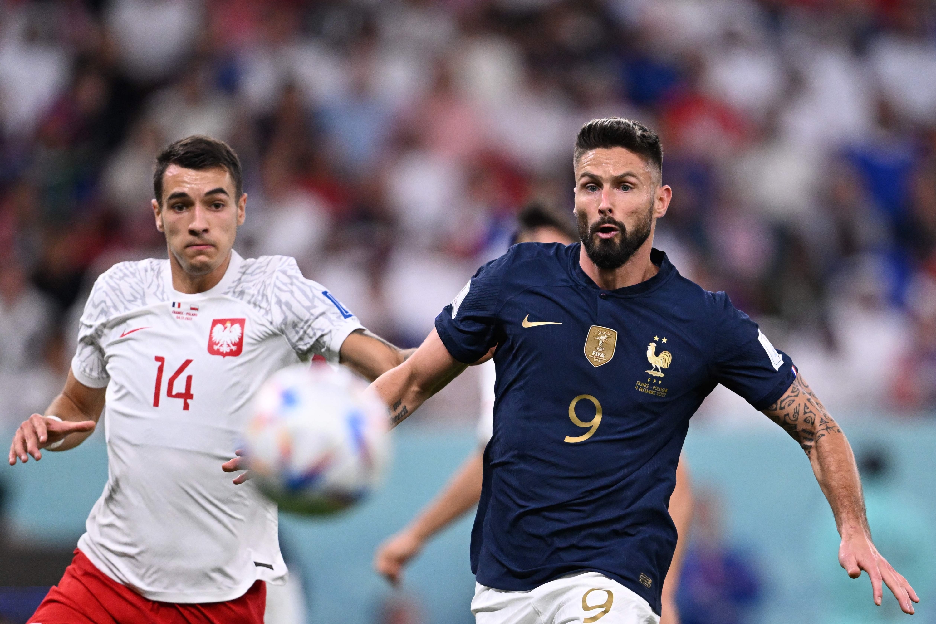 France's forward #09 Olivier Giroud (R) and Poland's defender #14 Jakub Kiwior run after the ball during the Qatar 2022 World Cup round of 16 football match between France and Poland at the Al-Thumama Stadium in Doha on December 4, 2022. (Photo by Kirill KUDRYAVTSEV / AFP)