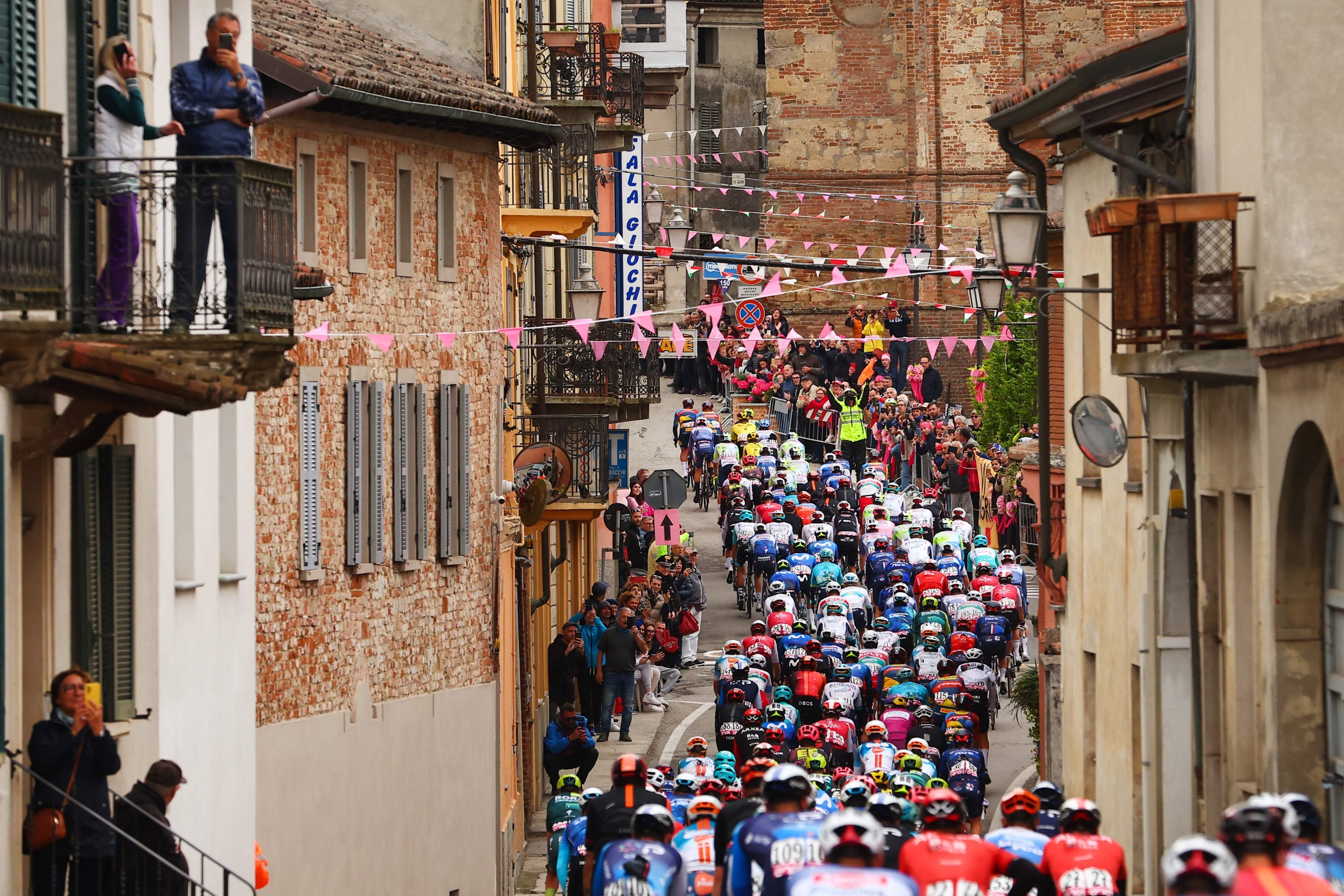 The pack rides in the village of Lu, near Alessandria, during the 3rd stage of the 107th Giro d'Italia cycling race, 166 km between Novara and Fossano, on May 6, 2024. (Photo by Luca Bettini / AFP)